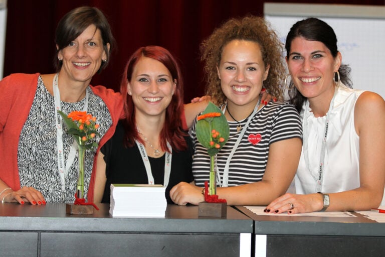 Vier Mitarbeiterinnen lächeln beim element-i Kongress in die Kamera