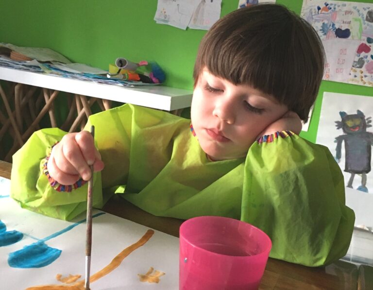 Kind malt mit Wasserfarben.
