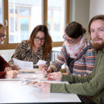 Drei Schülerinnen und ein Schüler sitzen an einem Tisch und arbeiten gemeinsam in der FDFP Karlsruhe.