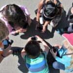 Eine Gruppe von Kindern kniet auf der Straße und schießt Fotos.