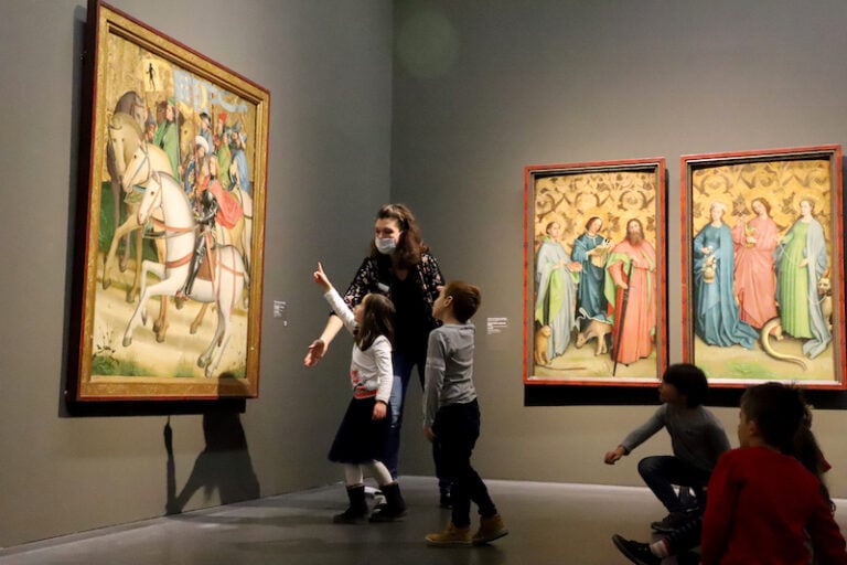 Frau und zwei Kinder schauen Bilder in Galerie an