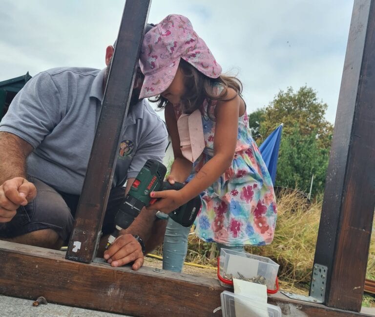 Brünettes Kind und Mann bauen mit Schraubenzieher